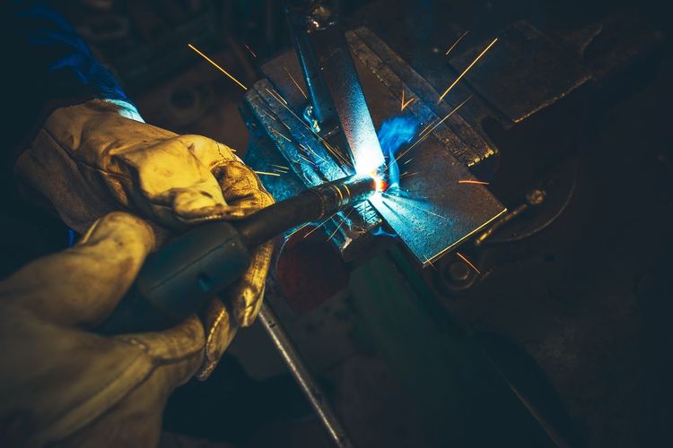 Cropped hands of worker welding metal in workshop