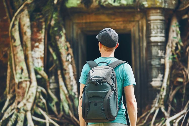 Rear view of young man with backpack standing in forest