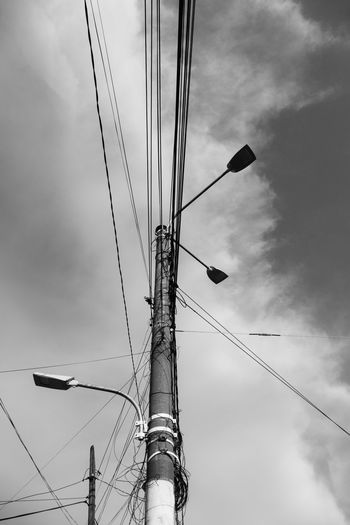 Low angle view of power lines against cloudy sky