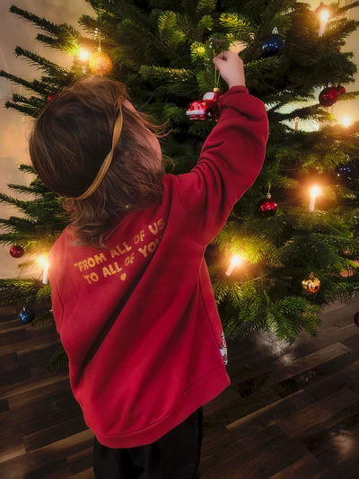 Rear view of woman standing against illuminated christmas tree