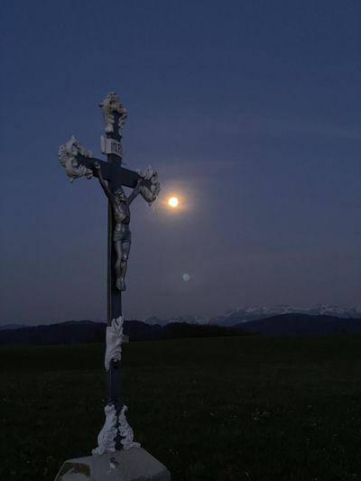 Cross on field against sky