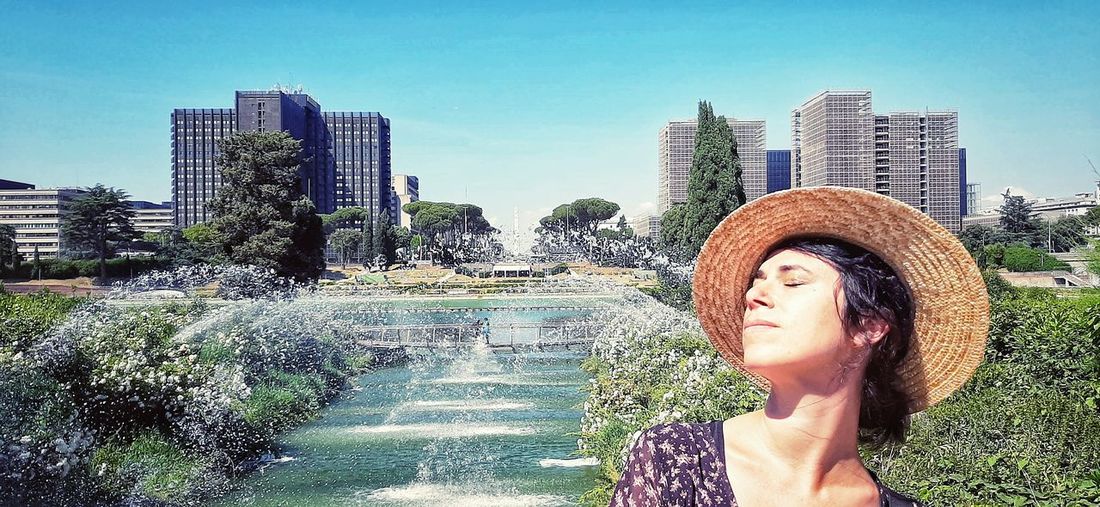 Portrait of beautiful woman in city against sky