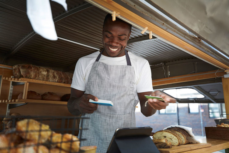 Smiling salesman holding credit card and reader in food truck