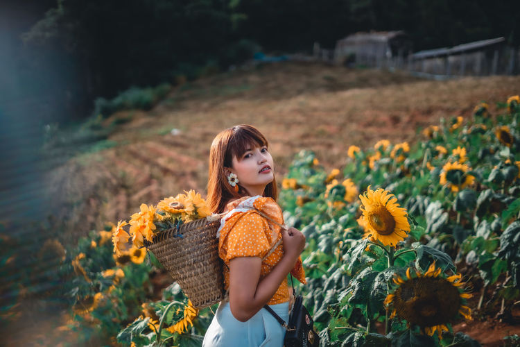 Portrait of smiling woman amidst sunflower field