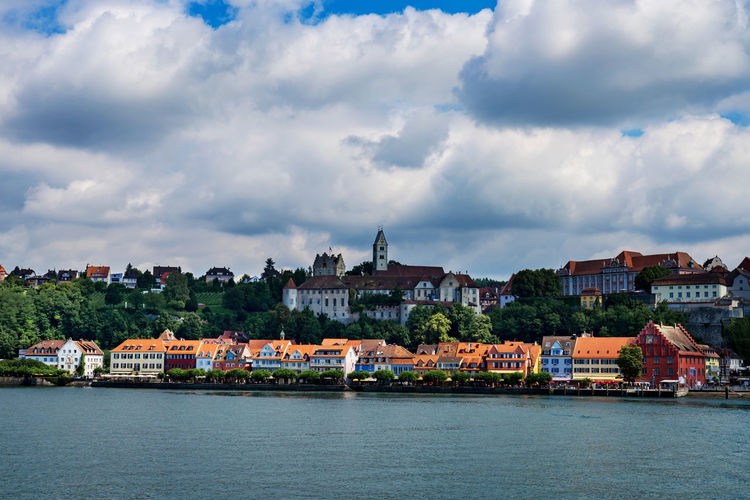 View of buildings at waterfront against cloudy sky