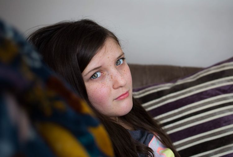 Close-up portrait of girl sitting on sofa at home