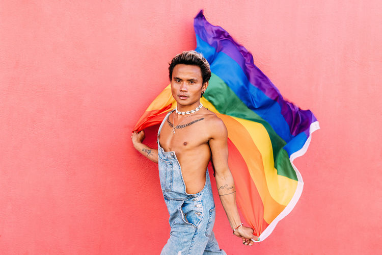 Portrait of smiling gay man holding rainbow flag