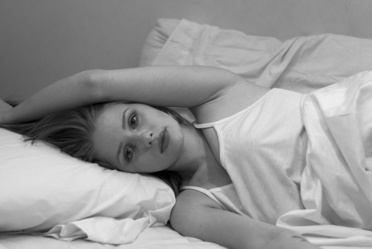 Portrait of young woman relaxing on bed