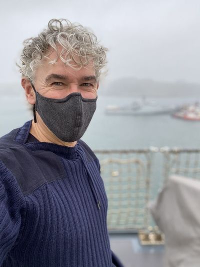 Portrait of mature man wearing mask standing against sea