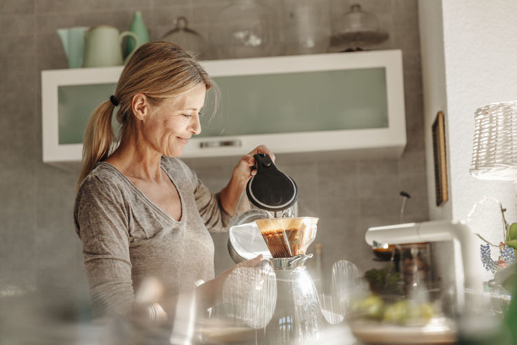 Woman at home in kitchen preparing coffee