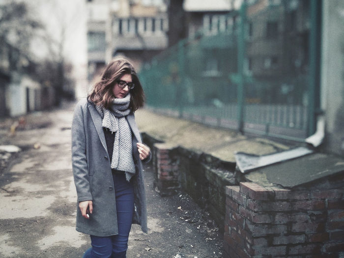 Young woman standing on footpath against building