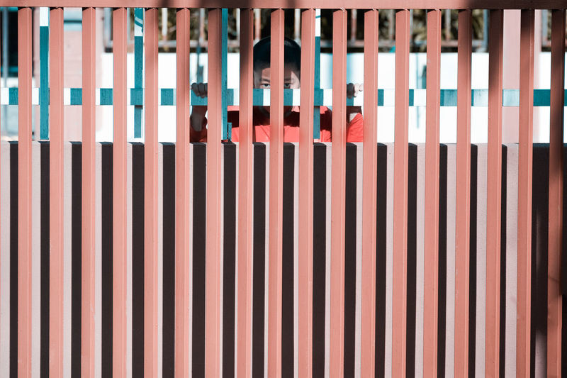 Boy standing behind patterned fence