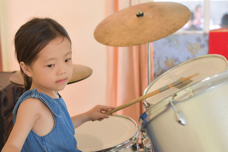Close-up of young asian girl playing drum.