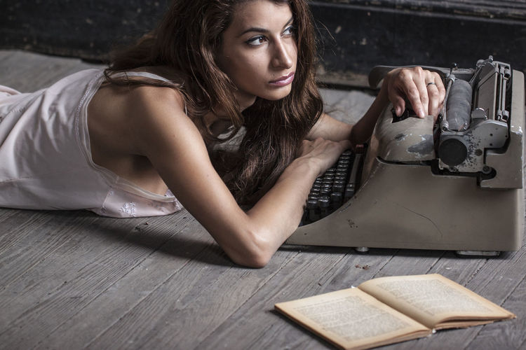Young woman lying by typewriter