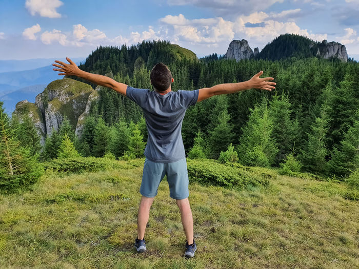 Rear view of man with arms outstretched standing on a mountain