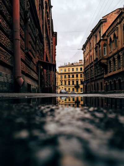 Surface level of puddle on street amidst buildings