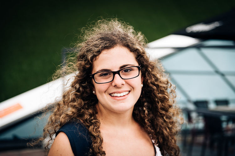 PORTRAIT OF SMILING YOUNG WOMAN IN EYEGLASSES