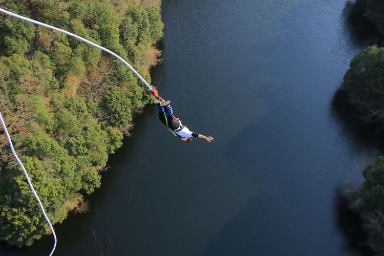 High angle view of man bungee jumping over river