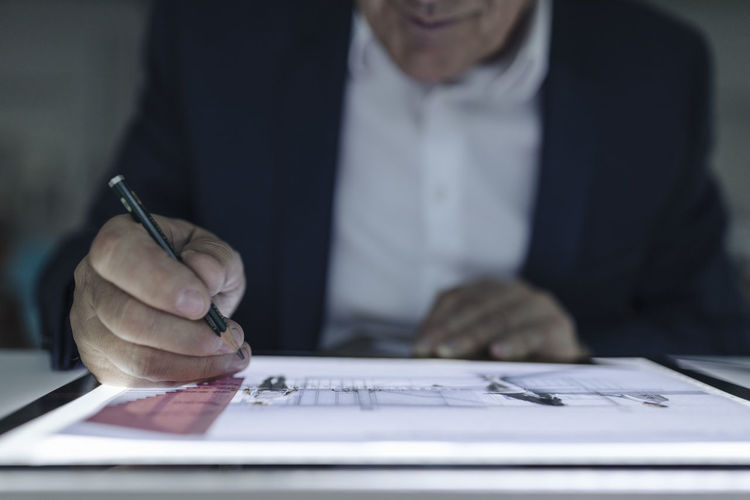 Close-up of senior businessman drawing on shining tablet