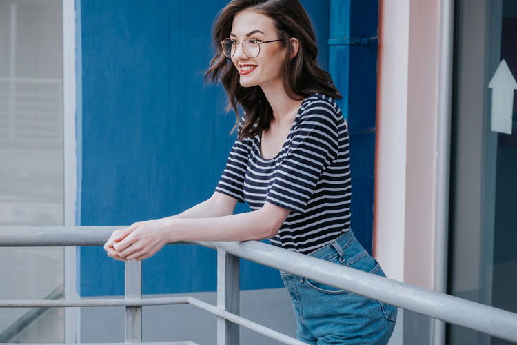 Young woman smiling against blue wall