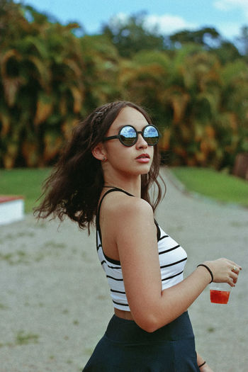 Side view portrait of teenage girl wearing sunglasses on field