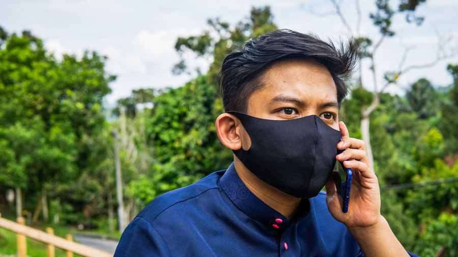 Young man wearing mask talking on phone outdoors