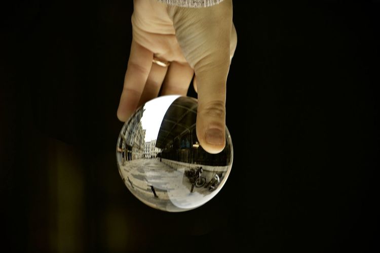 Low section of person holding crystal ball against black background