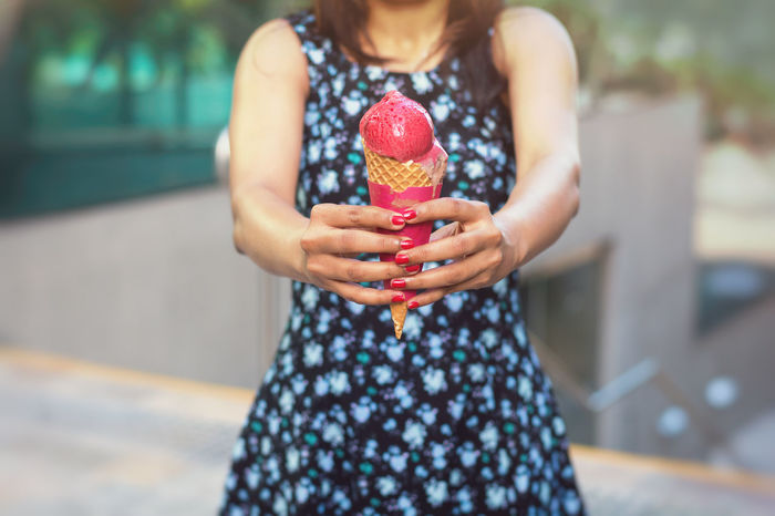 Midsection of woman holding ice cream cone while standing outdoors