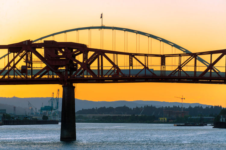 Bridges over willamette river against orange sky during sunset