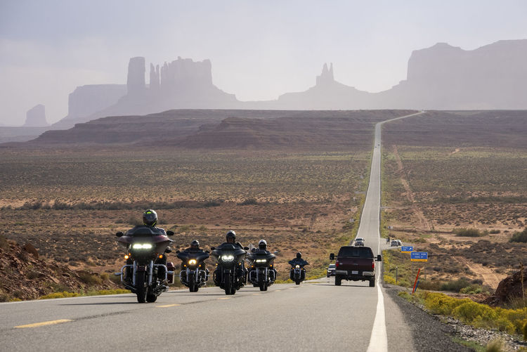 Tourists riding motorcycles on highway at monument valley park in summer