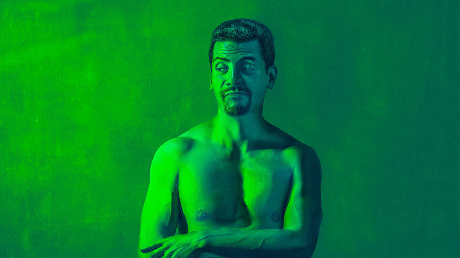 Shirtless man standing against wall