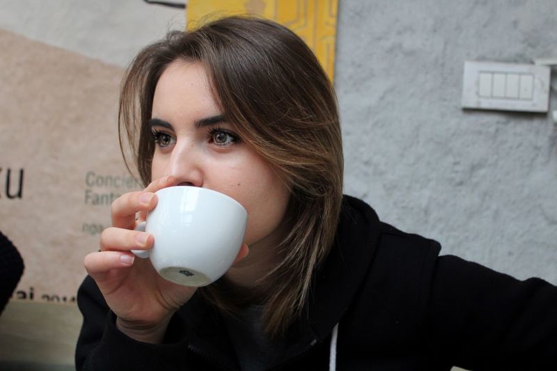 Close-up of young woman drinking coffee at cafe