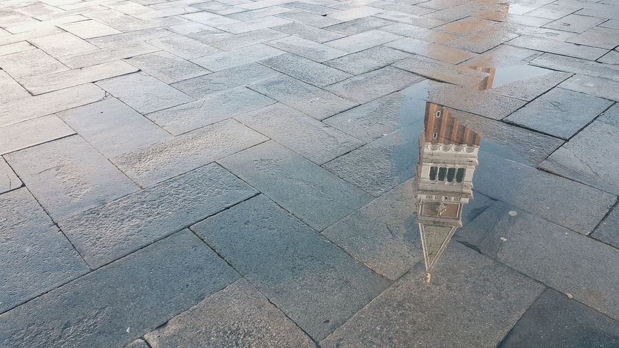 Reflection of san marco campanile on puddle at street