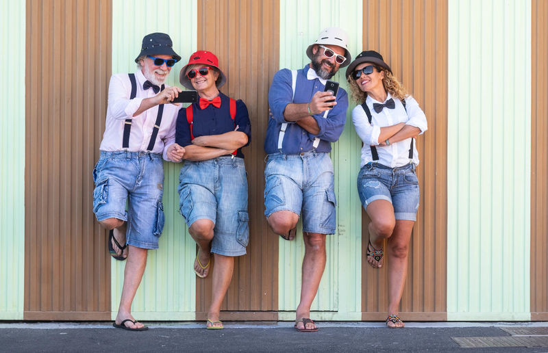 Smiling family using mobile phone while standing against corrugated iron