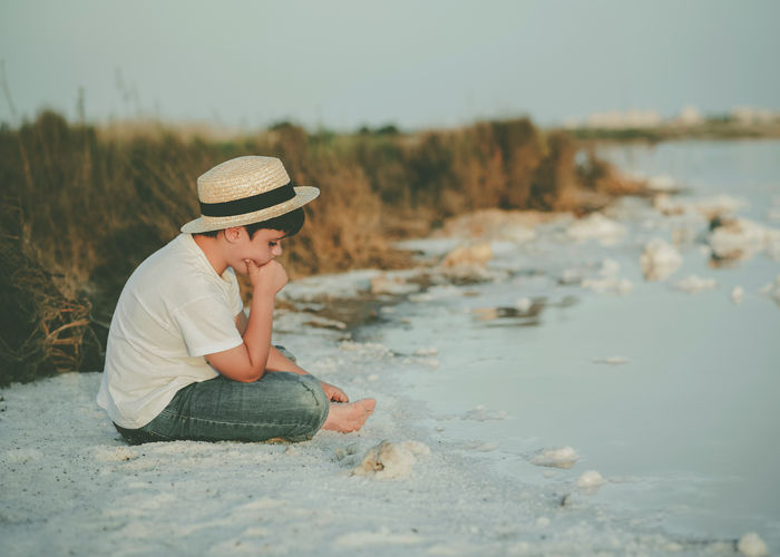 Side view of boy sitting at beach