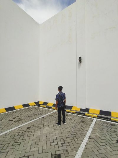Rear view of man standing against yellow wall