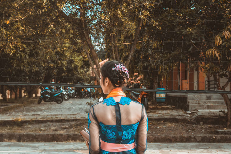 Rear view of woman standing against trees