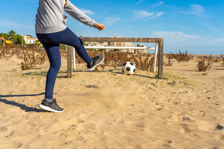 Low section of man playing soccer at beach