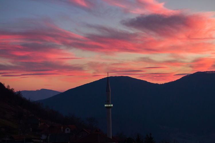 Silhouette of buildings against cloudy sky during sunset