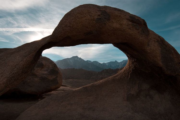 Mountains seen through hole in rock formation against sky