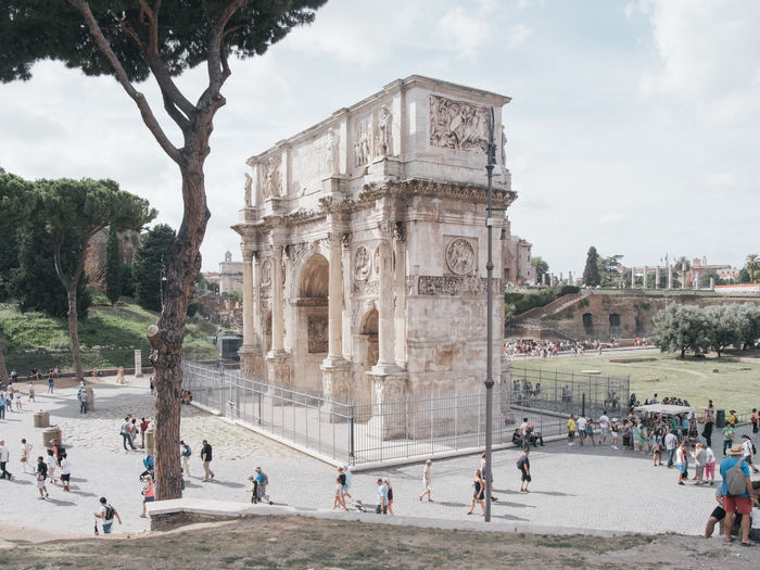 People at arch of constantine against sky