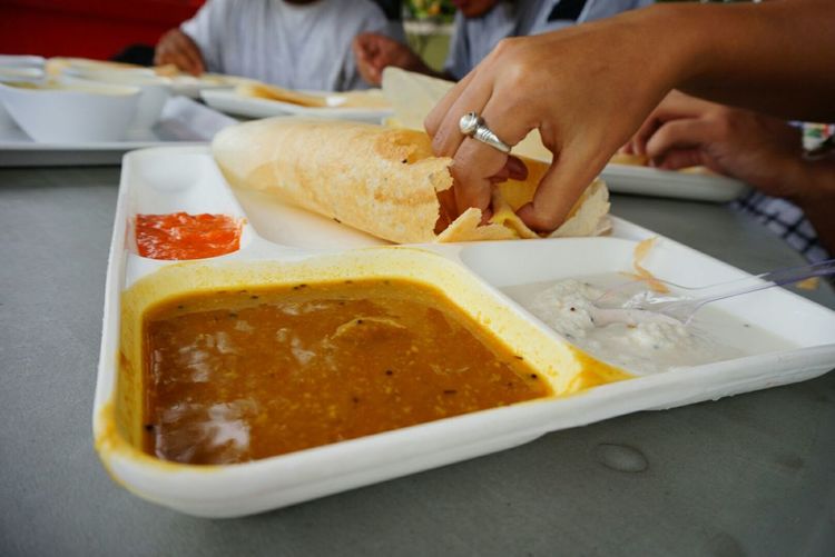 Cropped hand of man having thosai on table