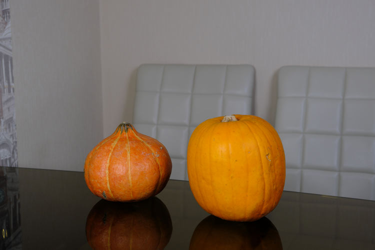 Close-up of pumpkins on table against orange wall