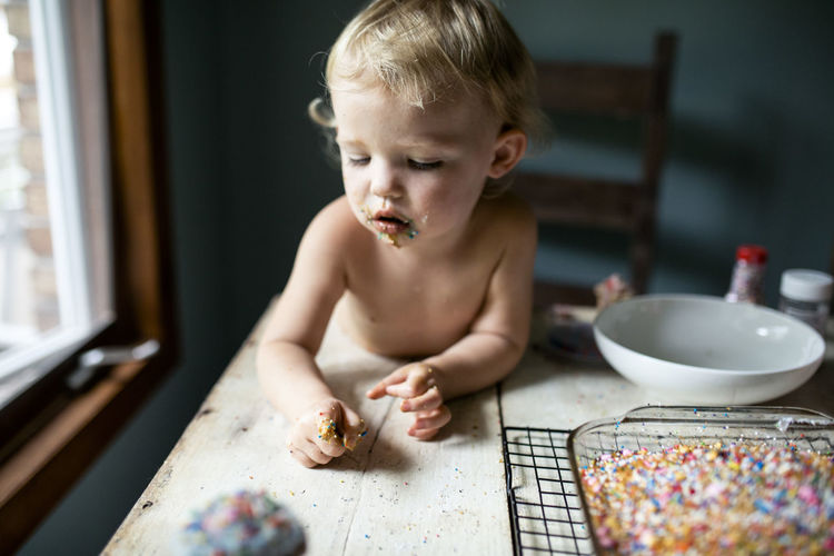 Little girl unsure of colorful sprinkle mess on her hand