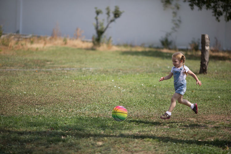 Girl playing with ball on grassy field