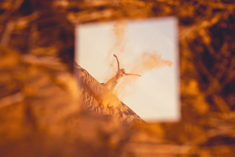 Reflection of woman spilling sand in mirror