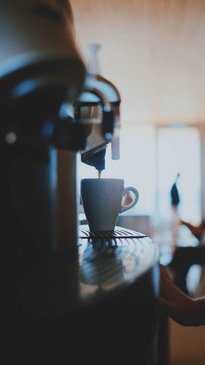 Coffee emitting from espresso maker in cup