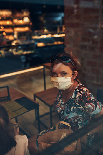 Portrait of woman wearing mask sitting at cafe