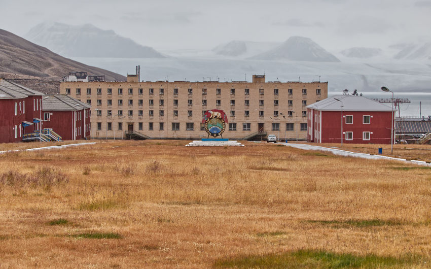 Ghost town in the arctic tundra of svalbard with a glacier in the background