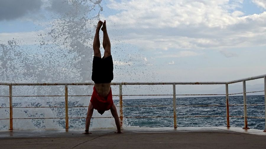 Man doing handstand by sea 